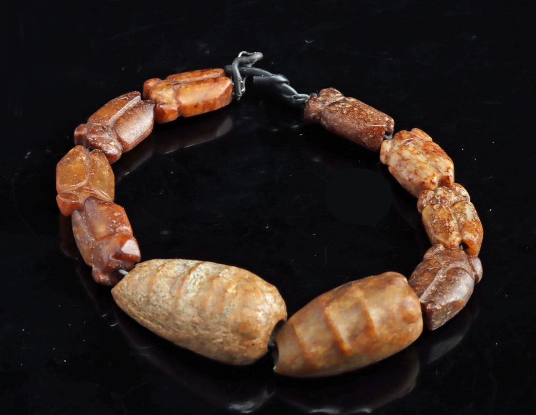 Chinese Zhou / Han Dynasty Jade Cicada Beads: East Asia, China, Zhou to Han Dynasty, ca. 1150 BCE–220 CE. A finely assembled ensemble of ten ancient jade cicadas carved from nephrite jade, now strung on a wire mount. XRF analysis confirms t