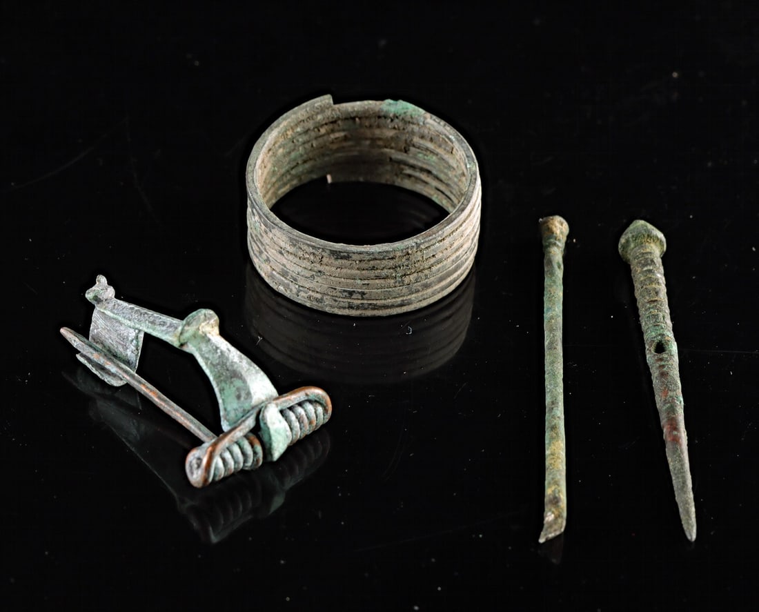 Ancient Bronze Group - Fibula, Hair Coil & Two Dress Pins: Western / Central Europe, Germany, Celtic / Roman cultures, ca. 500 BCE – 300 CE. A group of four ancient bronze personal adornments comprising a multi-coil hair ring with ribbed bands, a small 