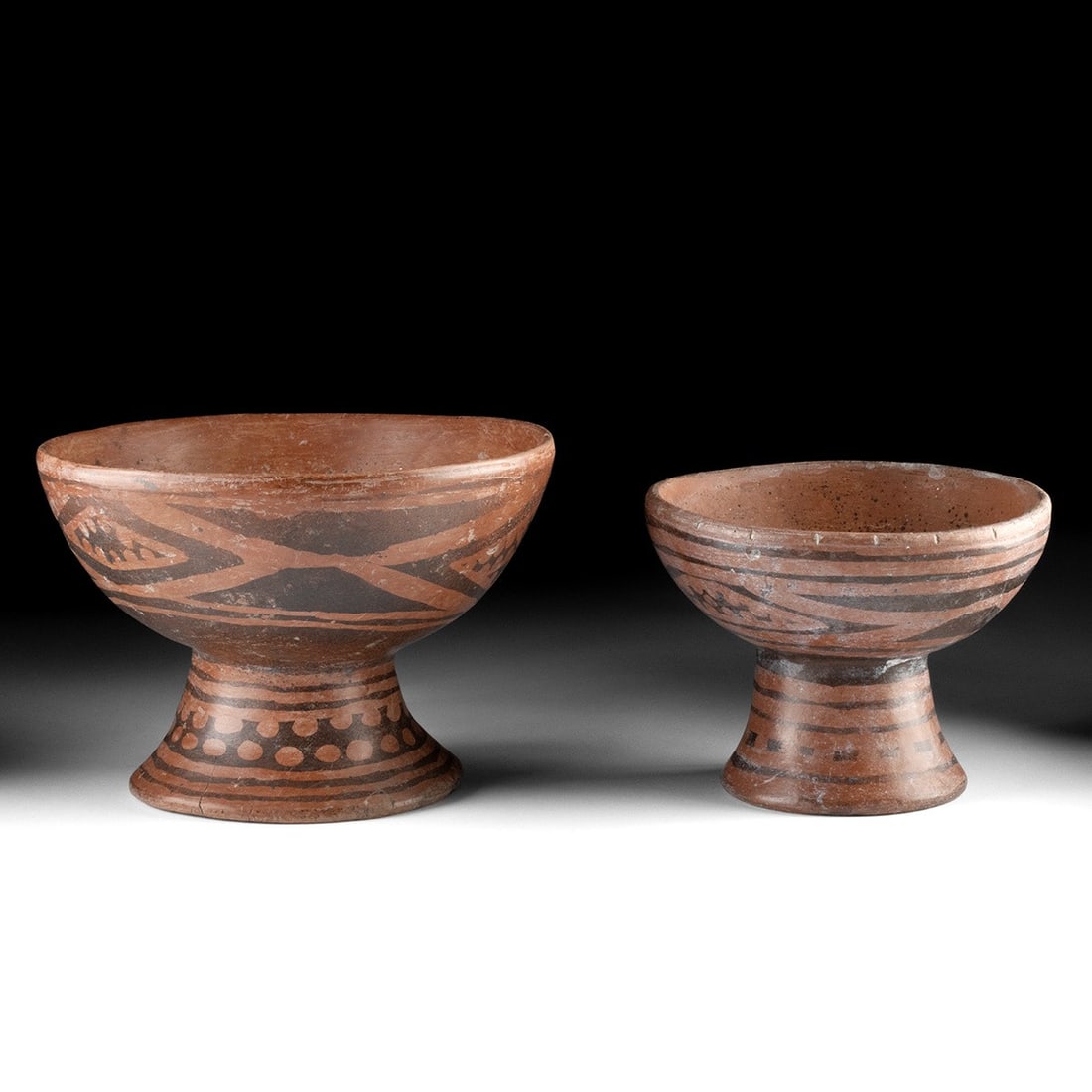 Pair of Narino Resist-Painted Pedestal Bowls: Pre-Columbian, Colombia, Narino culture, ca. 700 to 1500 CE. A pair of Narino pedestal bowls, one larger than the other, share the same assured form and decorative vocabulary: negative resist techniqu