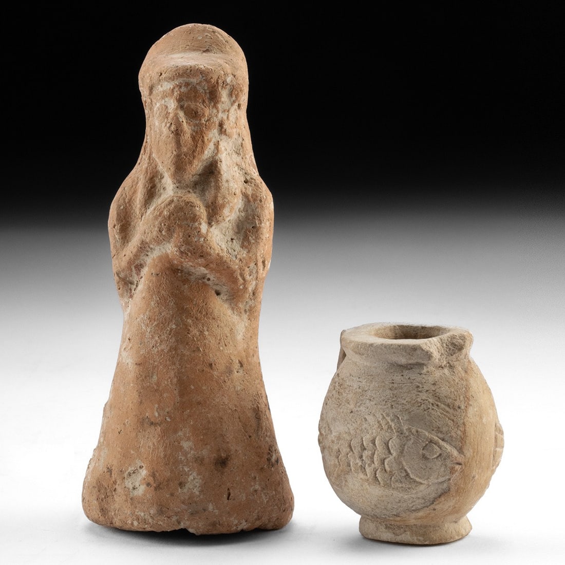 Iron Age Levant & Egypt - Votary Figure & Fish Jar, ex-Andrew C. Ware: Near East, Transjordan, Ammonite culture, ca. 9th to 7th century BCE; North Africa, Egypt, Late Dynastic to Ptolemaic period, ca. 664 to 30 BCE. A hand-modeled terracotta votary and a carved limestone