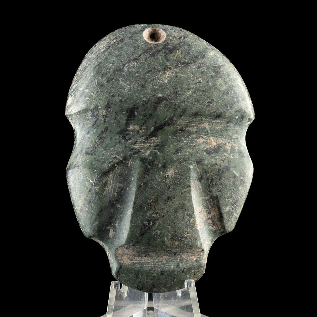 Pre-Columbian Mezcala Greenstone Maskette Pendant: Pre-Columbian, Mexico, Mezcala, ca. 500 BCE – 300 CE. A small greenstone maskette pendant carved in the classic Mezcala style, the schematic face reduced to essential planar forms with string-cu