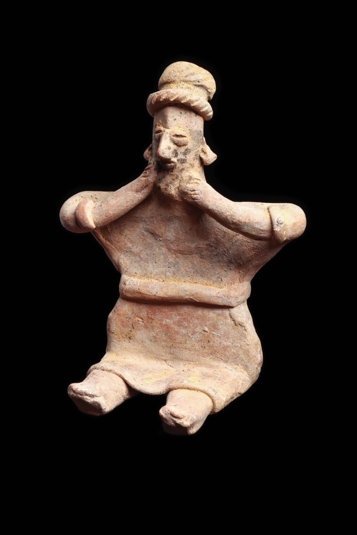 Colima Seated Woman Wearing Shirt: Colima, ca. 100 BCE – 250 CE. Solid pottery seated female figure holding both hands to her face, wearing a knee length skirt with belt, bracelets and rope type headband. Black painted decoration