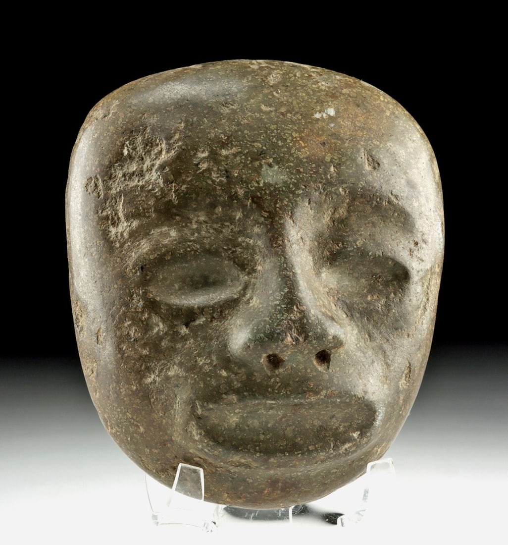 Teotihuacan Jade Maskette Pendant: Pre-Columbian, Central Mexico, Teotihuacan, ca. 200 to 600 CE. A jade maskette pendant. The stone is shaped into a rounded, tapering head with heavy lidded eyes, a long, narrow nose pierced with two n