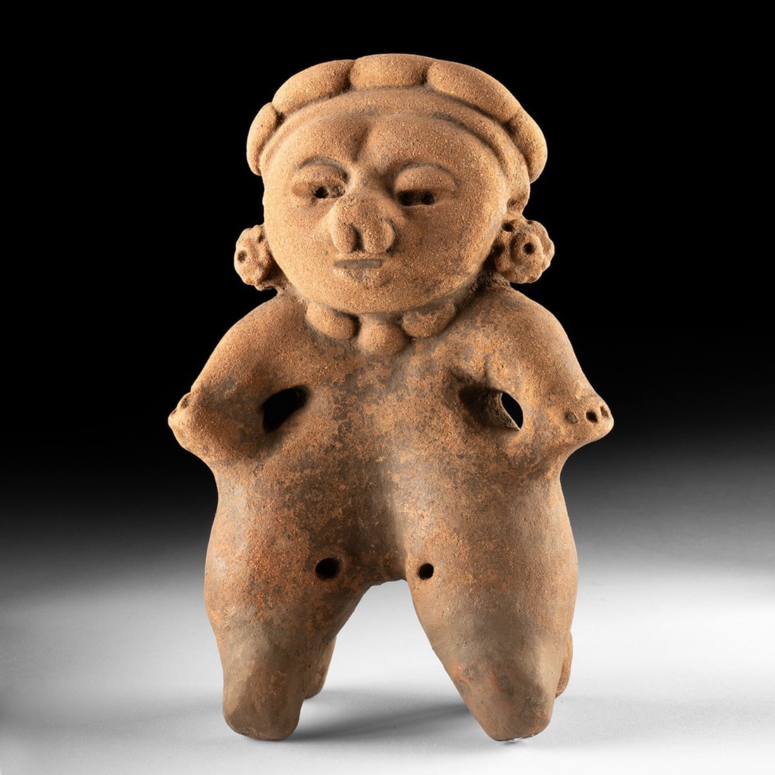 Proto-Maya Terracotta Rattle Figure, Standing Female: Pre-Columbian, Mexico, Maya, ca. 100 BCE – 500 CE. A standing female figure modeled in buff terracotta, hollow-bodied and doubling as a rattle whose clay pellets whisper when shaken. She stands 