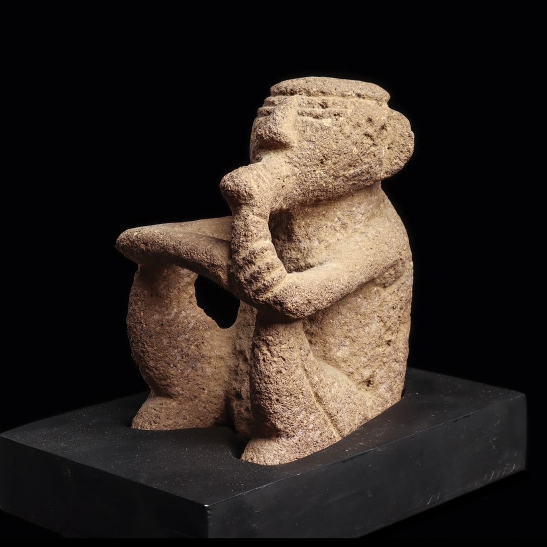 Costa Rican Sukia Figure: Costa Rica, Atlantic Watershed, ca. 10th–14th century CE. Carved gray volcanic stone male sukia figure, depicted sitting with both arms resting on raised knees, and holding a cigar to his mouth 