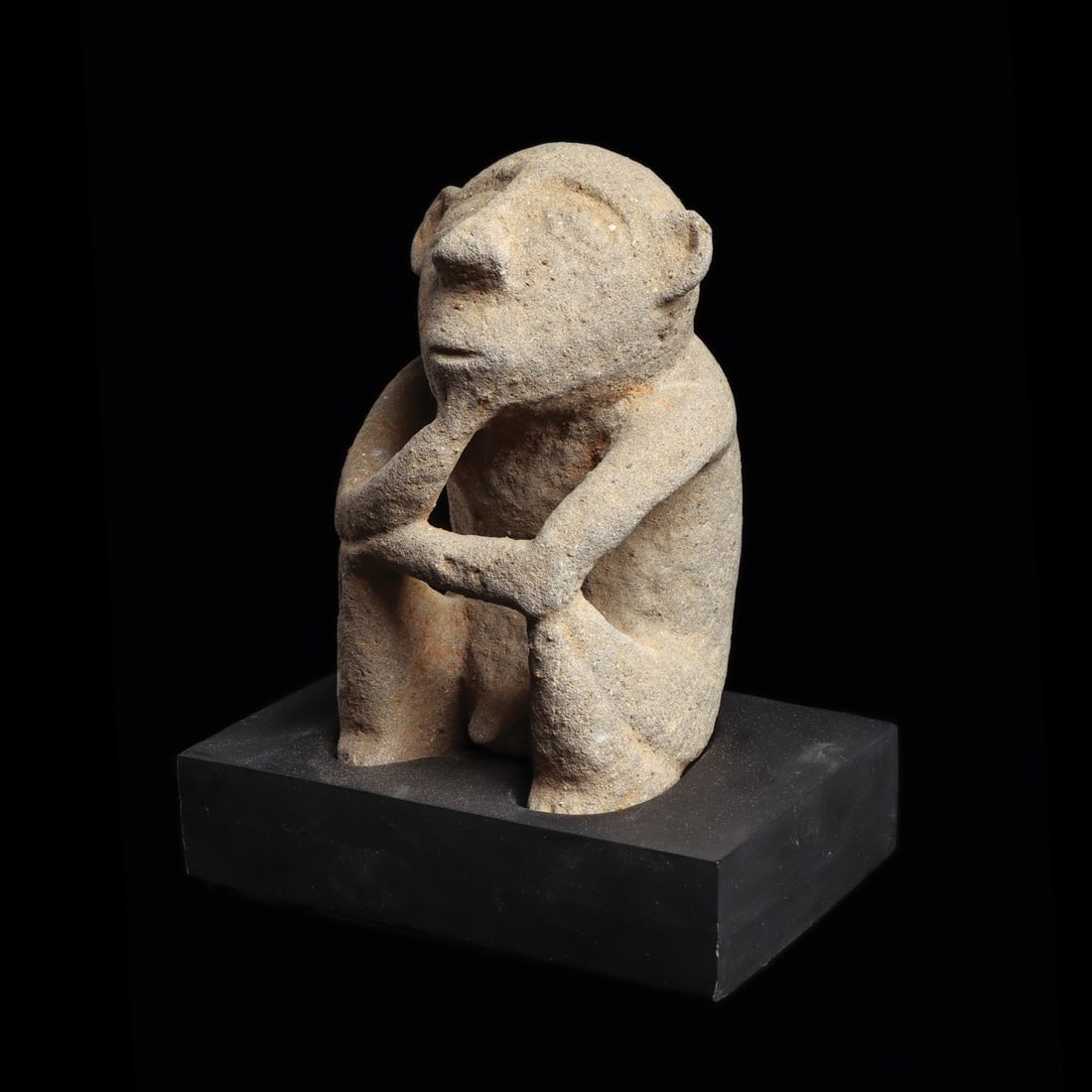 Costa Rican Stone Seated Figure: Costa Rica, Atlantic Watershed, ca. 10th–14th century CE. Carved gray volcanic stone male figure sitting with his arms resting on his raised knees, right hand held on his chin. Tapered head with