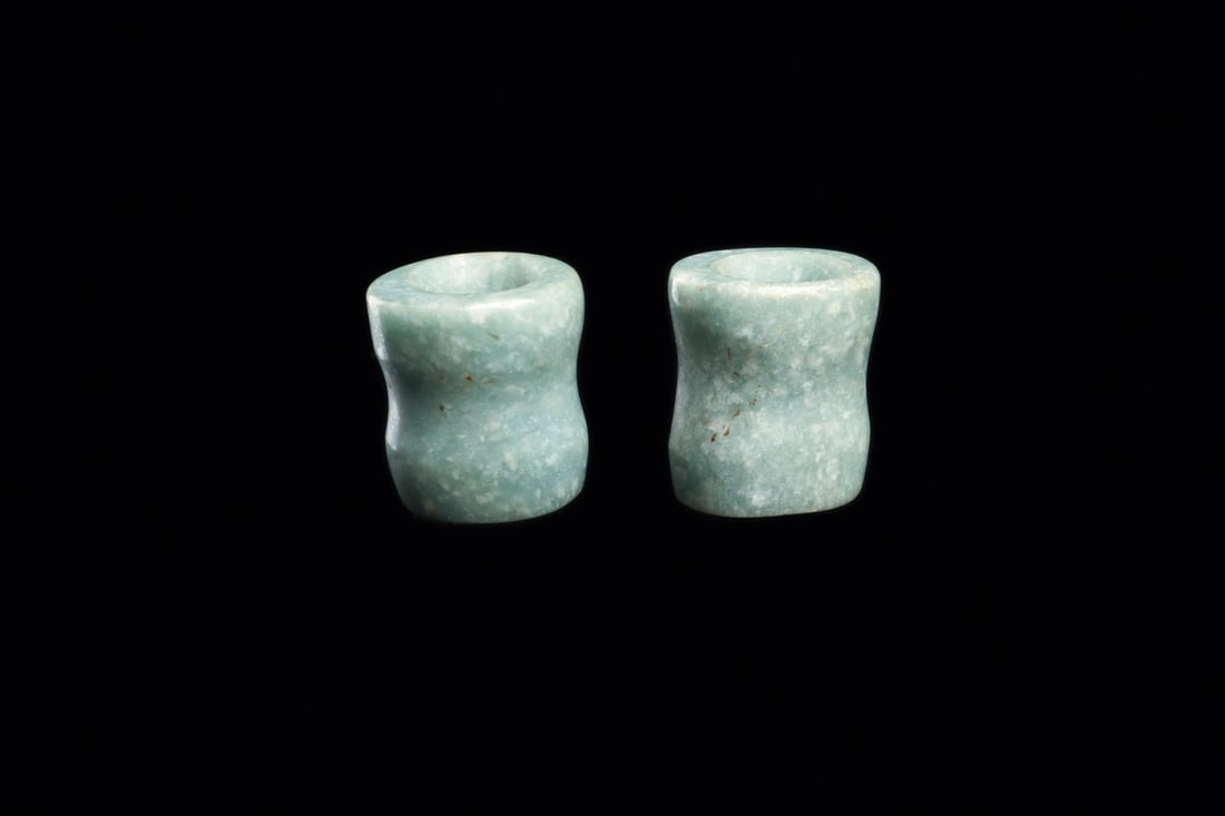 Costa Rican Jade Ear Plug Ornaments (2): Costa Rica, ca. 500–1000 CE. Matching pair of medium blue-green jade ear plug ornaments, flared from the center and rounded opposing end to fit into one’s ear, drilled through their center