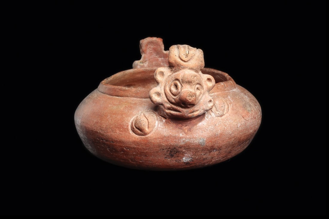 Taino Decorated Vessel with Projecting Heads: Hispanolia, ca. 1000–1425 CE. Salmon-brown pottery bowl decorated with two opposing heads with high hairdos. 8.25" L × 6.75" W (20.96 cm L × 17.15 cm W). Provenance: Private Florida co
