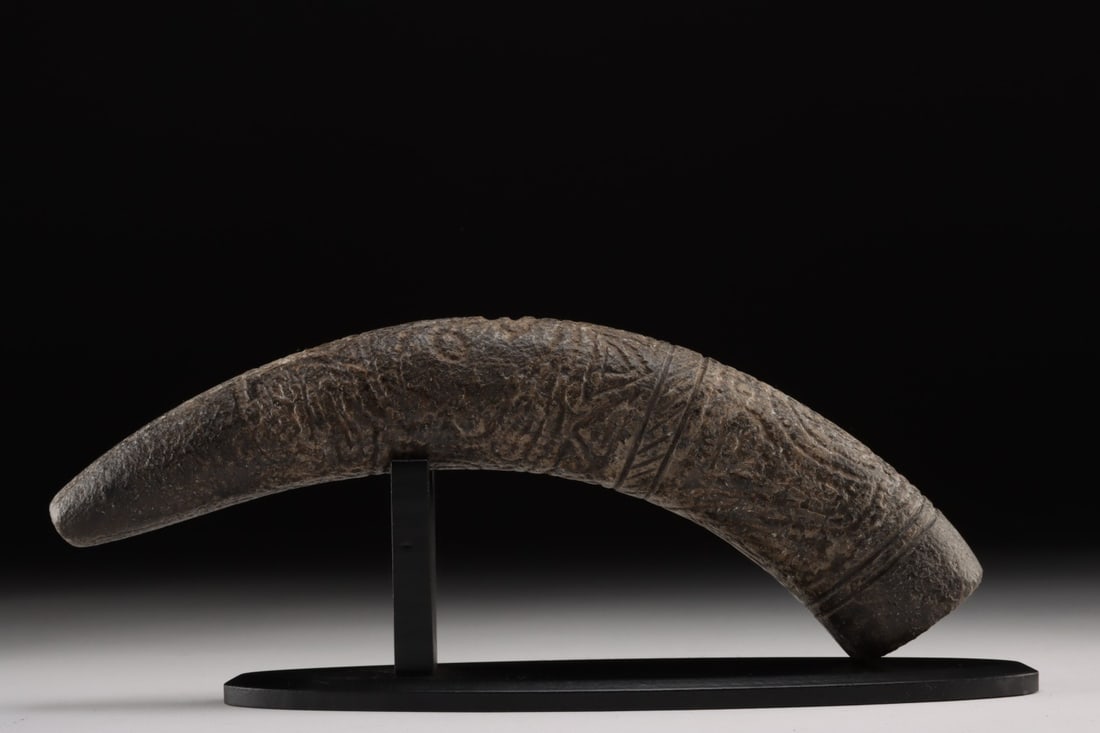Pre-Columbian Taino Stone Pestle - Ritual Zemi Motifs: Pre-Columbian, Greater Antilles, Taíno culture, ca. 1000 to 1500 CE. A finely carved stone pestle with an elongated, gently curving form, tapering to a rounded point. The surface bears a dense we