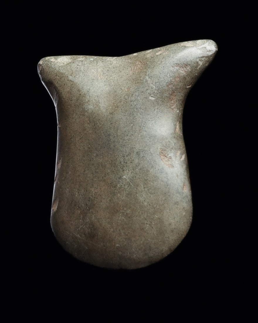 Valdivia Votive Stone Axe: Ecuador, ca. 2300–2200 BCE. Carved greenish-gray hardstone stylized fish-form axe with elegant rounded torso and a pointed fish tail. Single edge crescent blade. Original matte-finish polished