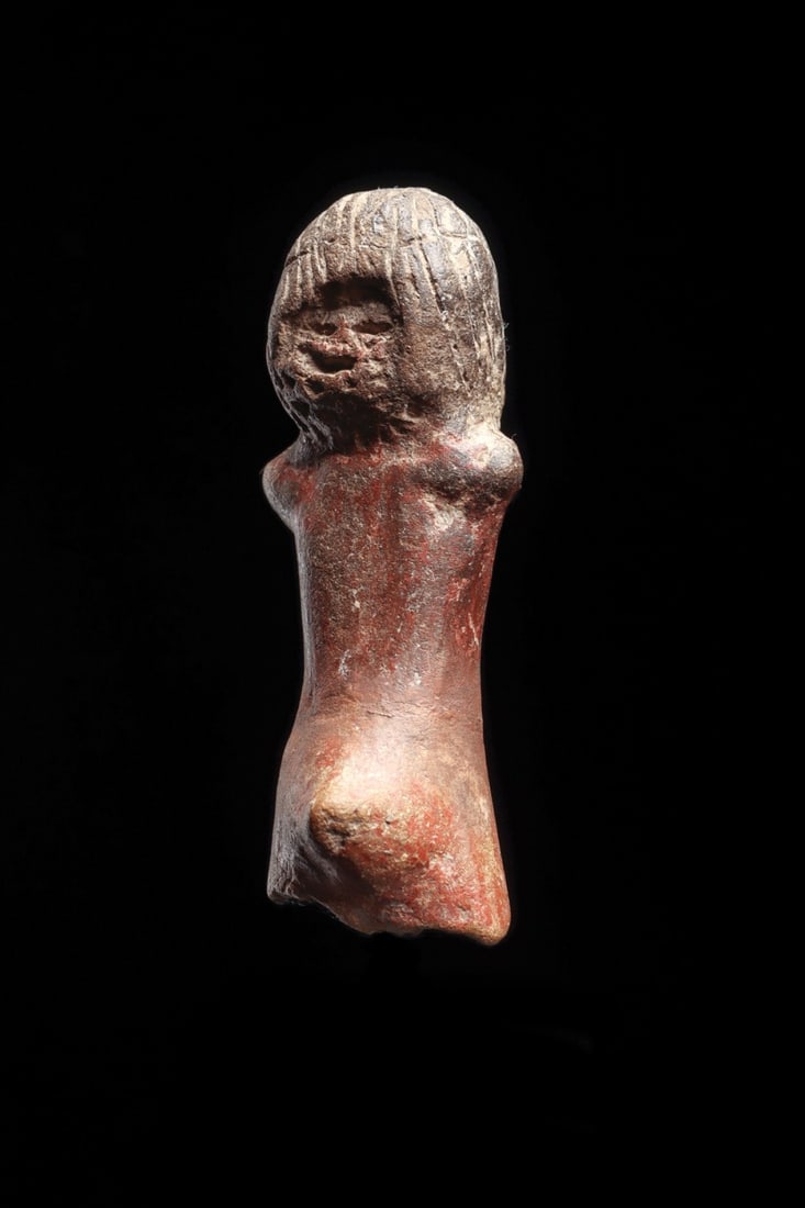Valdivia Male Figure: Ecuador, ca. 3500 BCE. Solid pottery standing male idol, depicted with a long hairdo with incised striated details, very simple facial figures, stubby arms and pointed penis. Some remaining red-brown 