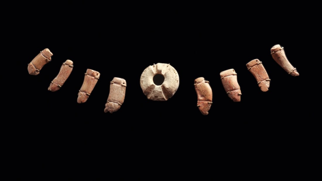 Chavin Archaic Necklace Bone Phallus & Disk Necklace Elements (9): Jequetepeque River, ca. 1200 BCE or earlier. Group of nine carved bone necklace elements, including eight similar stylized penis pendants with drilled suspension holes and a disc pendant divided into