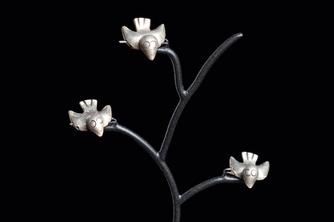 Moche Silver Sea Birds on Tree Stand (3): North Coast, ca. 300–500 CE. Three hollow silver avian beads, all have spread wings, a fan tail, and small circular eyes. Perforated through their wings for stringing. Mounted on a custom tree f