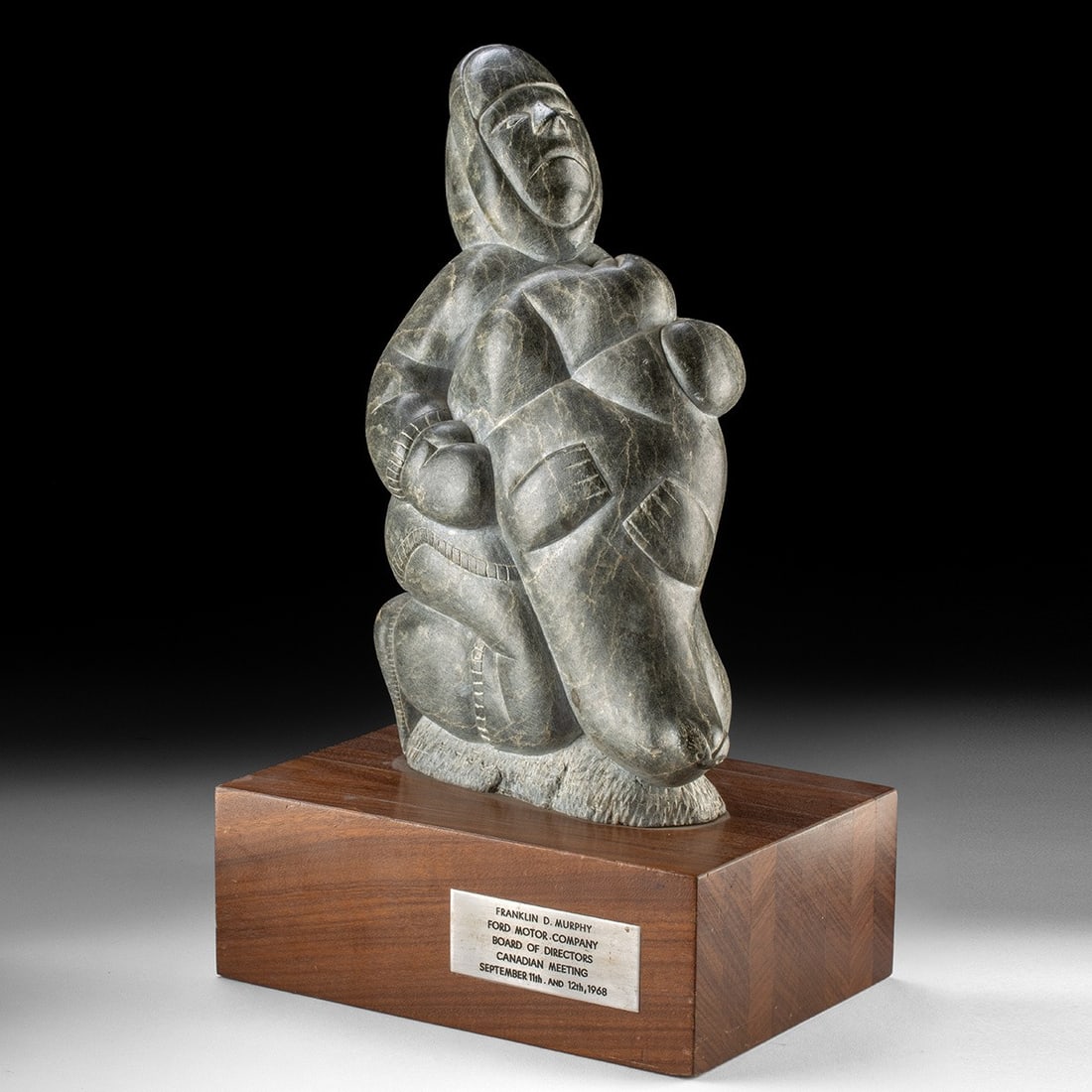 Inuit Soapstone Seal Hunter with Catch | Ford Motor Co.: Native American, Canadian Arctic, Inuit, ca. 1960–1968 CE. A hunter crouches low over his prize, arms folded around the sleek bulk of a seal drawn up against his body. Carved from dense grey-gre