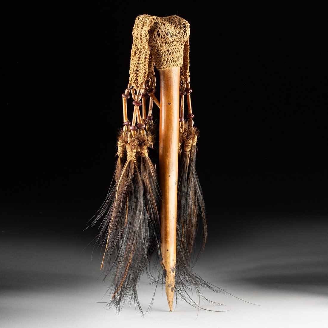 Papua New Guinea Bone Dagger - Cassowary Feathers & Woven Fiber: Melanesia, Papua New Guinea, ca. mid-20th century CE. A bone dagger fashioned from a sharpened animal or bird bone, its blade tapering to a barbed point. The handle is wrapped and mounted with a