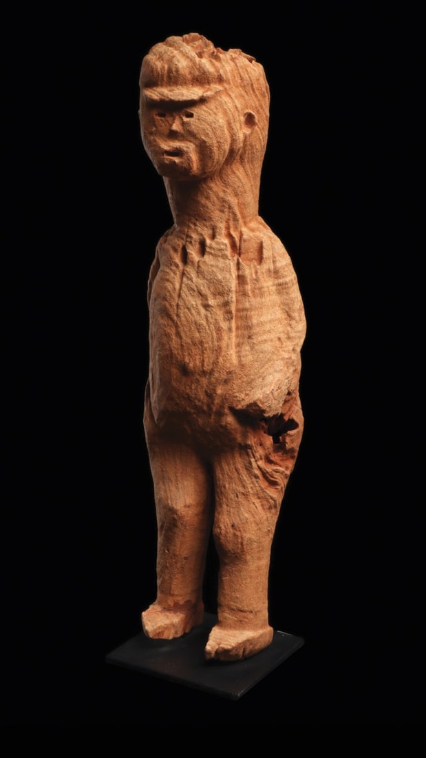 Togo Figure: Togo. Tall figure of a male youth carved with short brimmed cap, face expressed with small horizontal depressions, small round ears, and arms at sides. Dry weathered orange-brown patina with visible l