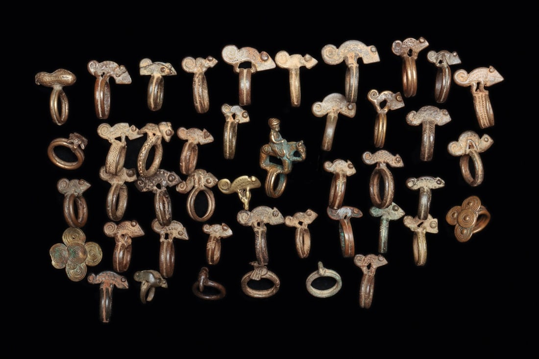 Senufo or Lobi Chameleon Rings and More (44): Ivory Coast and Burkina Faso. Large group of copper alloy rings mostly chameleon rings of different forms, a few feature a pair of chameleons. One ring displays a horse and rider, another with a peanu