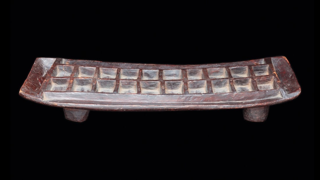 Mancala Gameboard: Ethiopia. Konso-Oromo gameboard with 20 squared playing holes, standing on four thick cylindrical legs. Exc. cond. Deep brown patina. Mancala games have been know and played for thousands of years.