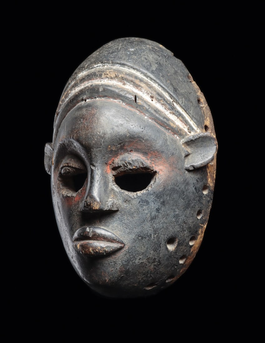 Ibibio Mfon Ekpo Mask: Nigeria. Classic and old “mfon ekpo” mask of an idealized female, carved with a tight cap over the hairline, open eyeholes beneath defined lids, full lips, and thick remnants of white kaol