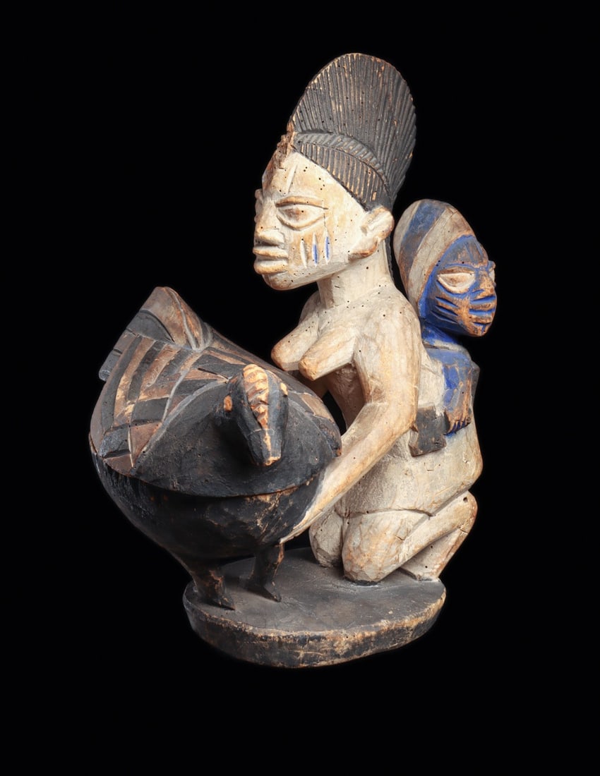 Yoruba Maternity Olumeye "One-Who-Knows-Honor": Nigeria. Depicting a kneeling woman regarded as a messenger between the human and spiritual realms. She supports a lidded offering bowl in the form of a cockerel, while carrying a child upon her back