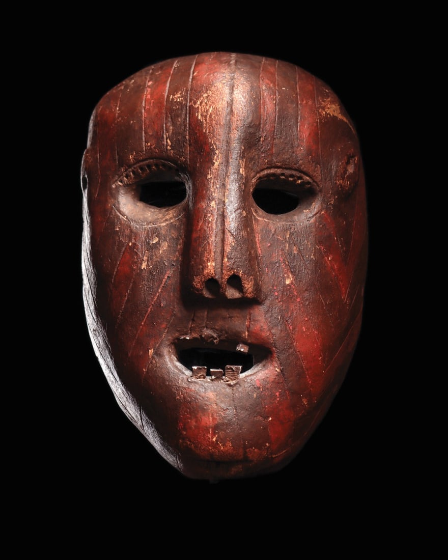 Tanzania Mask: Tanzania. Deeply carved anthropozoomorphic mask, possibly with lion features, the surface engraved and painted with alternating red and black lines, open mouth with wood peg teeth, eyes would have hel