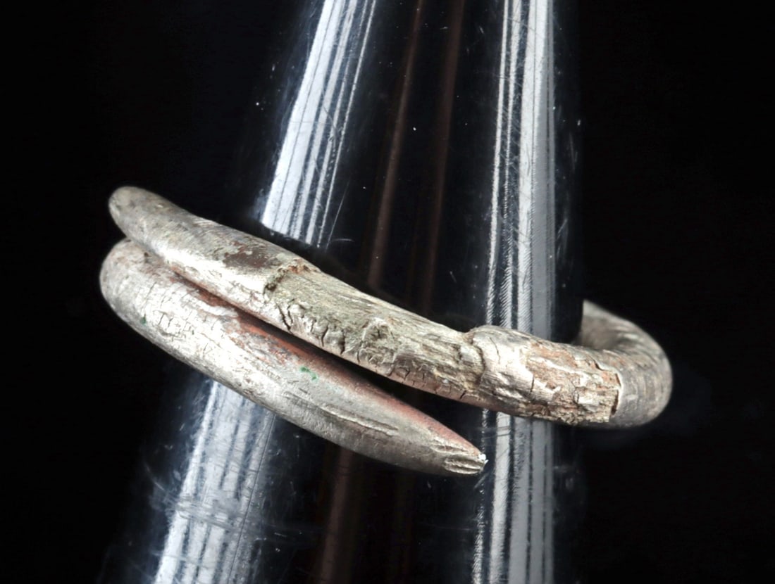 Ancient Roman Silver Hair Ring, Coiled Wire, 1st-3rd Century CE: Roman, Imperial period, ca. 1st to 3rd century CE. An ancient Roman silver hair ring, fashioned from a thick, rounded wire coiled into an open loop, with tapered ends overlapping slightly. It would ha