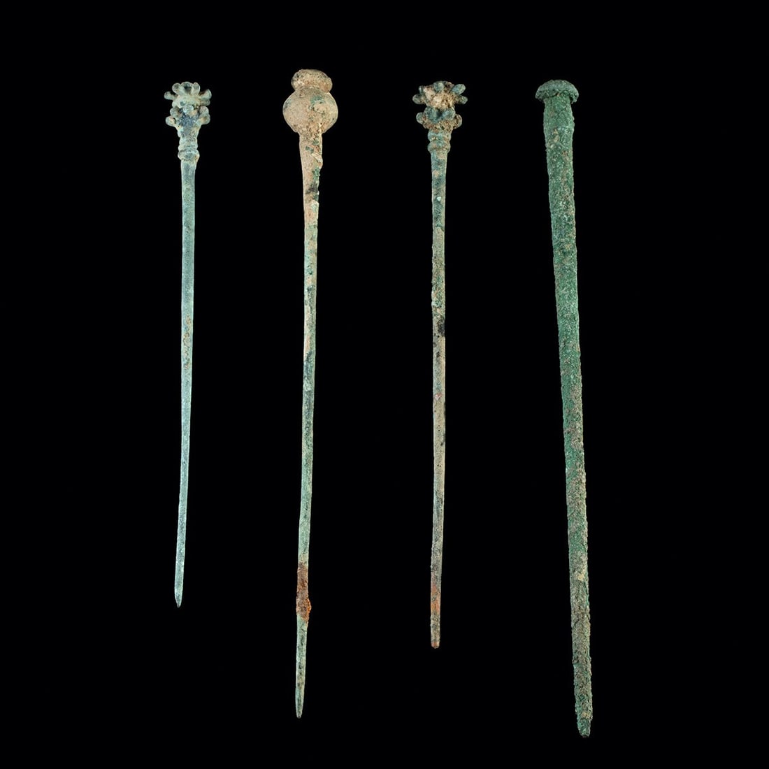 Group of 4 Luristan Dress Pins, Varied Finials: Near East, Turkey / Iran, Luristan, ca. 100–300 CE. Four bronze and copper dress pins with long tapering shafts, that carry varied decorative heads: one has a bulbous poppy-pod finial, one a fla