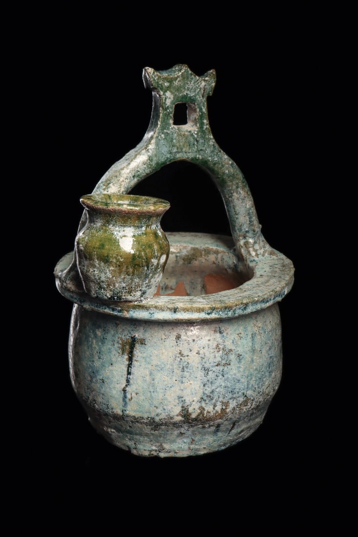 Eastern Han Dynasty Glazed Pottery Well: China, han Dynasty, ca. 206 BCE – 220 CE. Blue-green glazed pottery bowl depicting a well, having a basket type handle with a stylized temple type finial, and a smaller dipping vessel on the rim