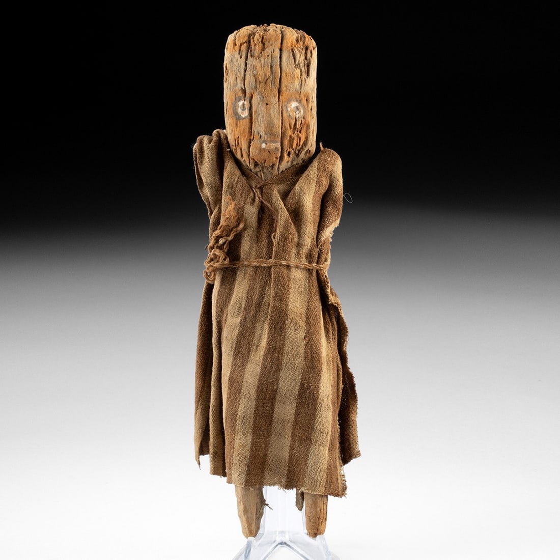 Chancay Wood Burial Doll - Striped Cotton Tunic: Pre-Columbian, Peru, Chancay, ca. 1000–1470 CE. A carved wood burial figure of simplified form, the flat face painted with stylized red and white features in the manner seen on wooden funerary m