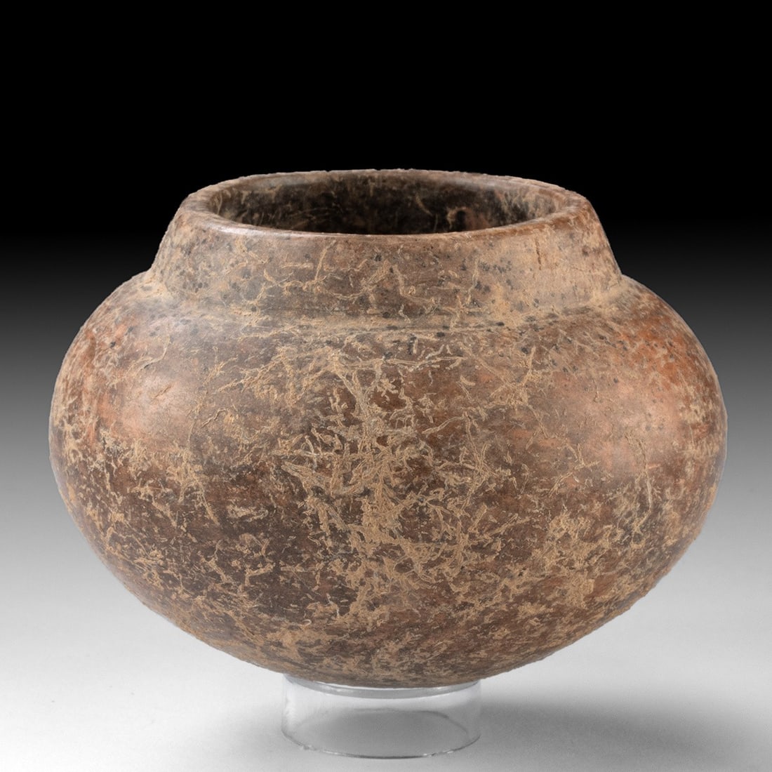 Colima Redware Jar - Globular Olla with Mineral Encrustation: Pre-Columbian, Mexico, Colima, ca. 300 BCE – 300 CE. A squat globular olla thrown from earthenware and burnished to a warm reddish-brown slip, its low profile swelling from a rounded base to a s