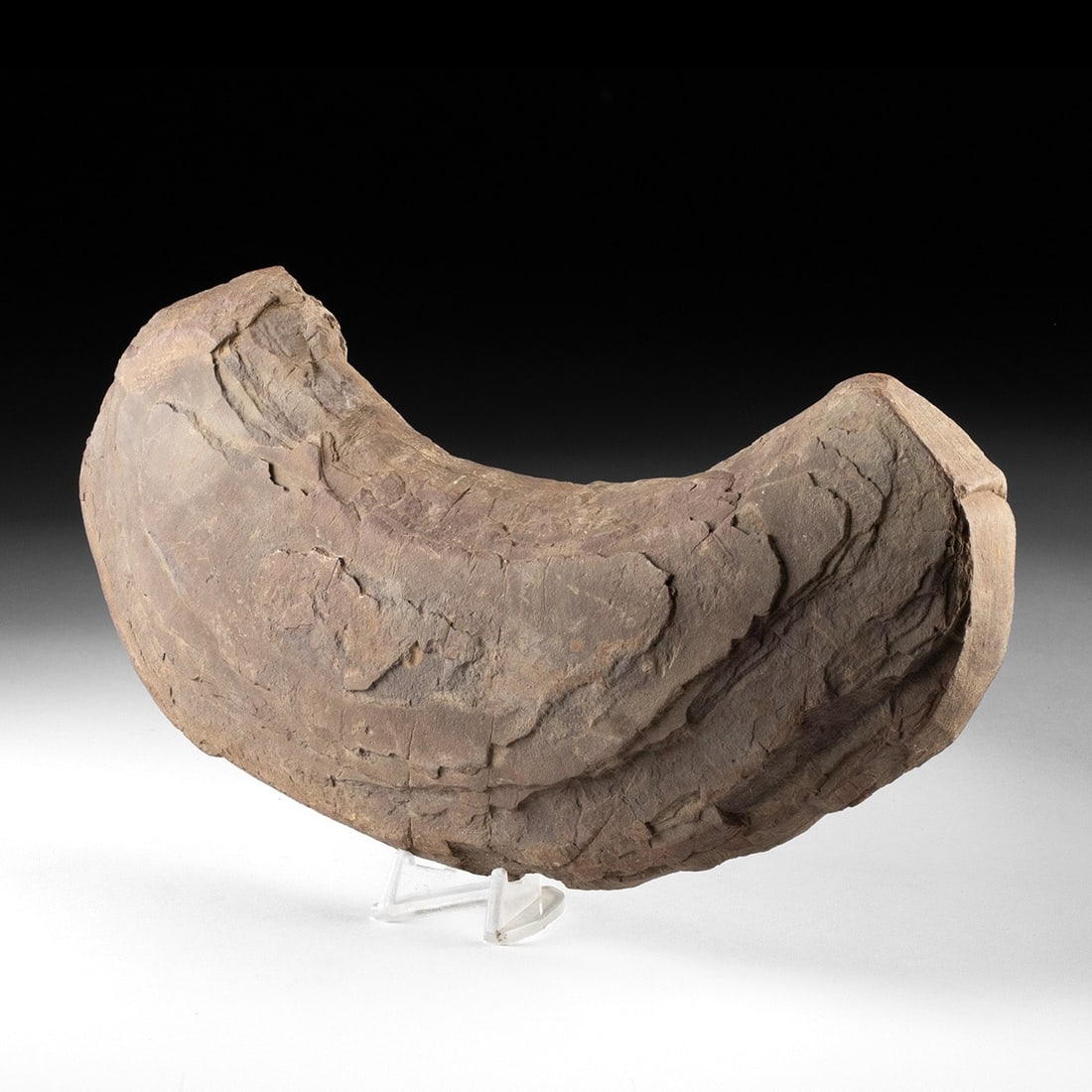 Large Native American Carved Stone Implement: Native American, South Central United States, ca. 3000 BCE – 1500 CE. A weighty curved, russet sandstone, shaped by patient abrasion into a crescent form. The surface bears flaking and weatherin