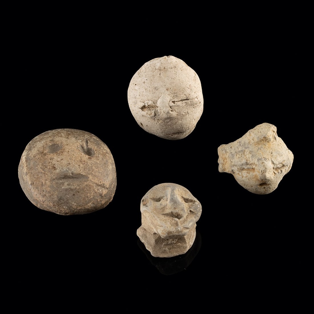 Four Mississippian Pottery Head Effigy Rim Riders, Arkansas: Native American, Mississippian culture, ca. 1200–1500 CE. A quartet of modeled clay faces, each no larger than a thumbprint, gazing out across the centuries with the spare, hollow-eyed gravitas 