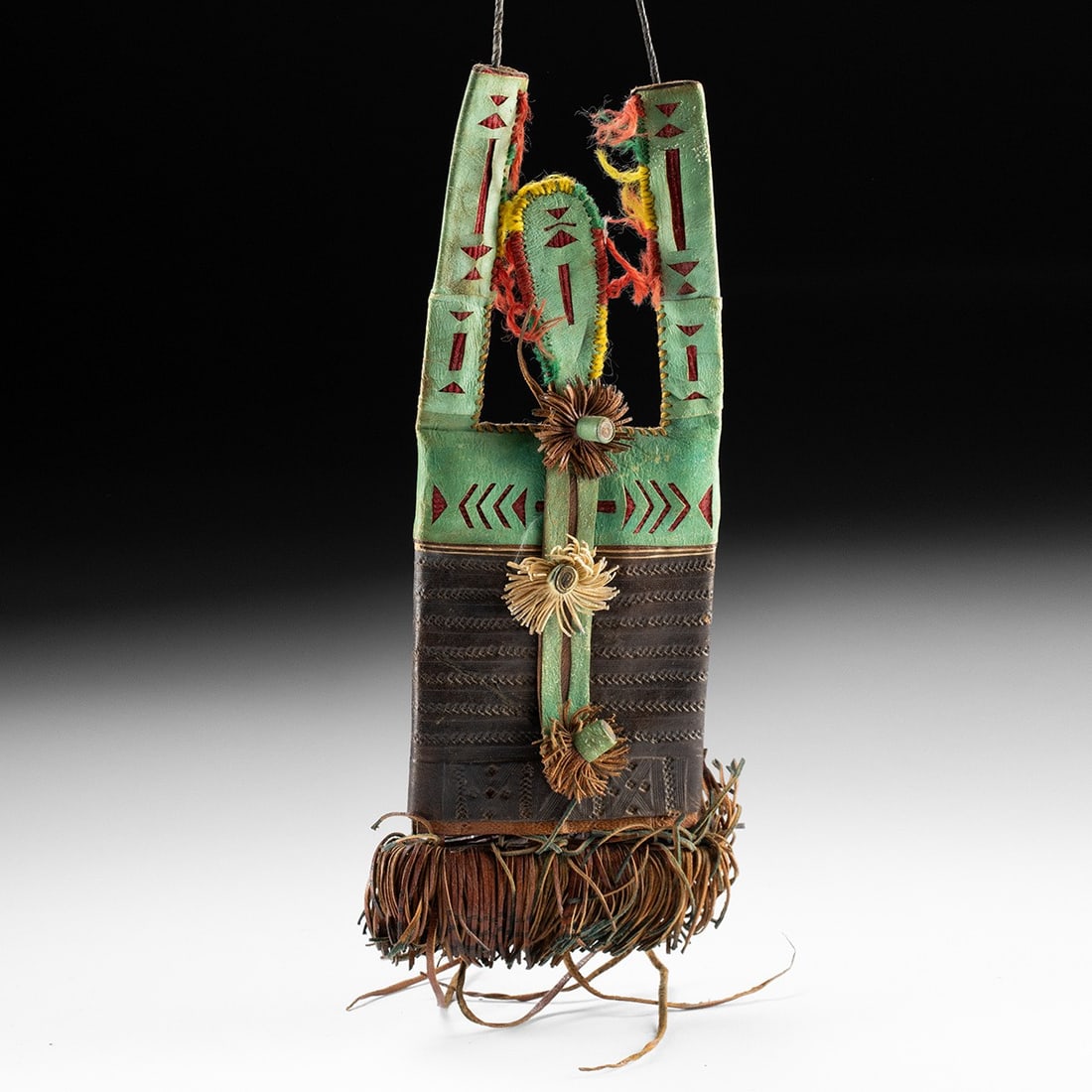 Tuareg Berber Leather Saddle Decoration - Green Dye Openwork & Yarn: North Africa, Tuareg people, Berber culture, ca. mid-20th century CE. A green-dyed leather saddle tassel, its surface cut with openwork designs revealing a red felt lining in geometric bands of triang