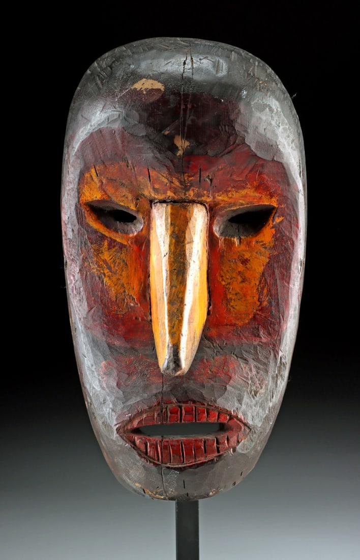 Vibrant Borneo Dayak Tribal Wood Ritual Mask: Southeast Asia, Indonesia, Borneo, Dayak culture, ca. early to mid-20th century CE. A boldly carved wooden mask presenting a simplified visage with deeply recessed eyes, a long projecting nose, and a 