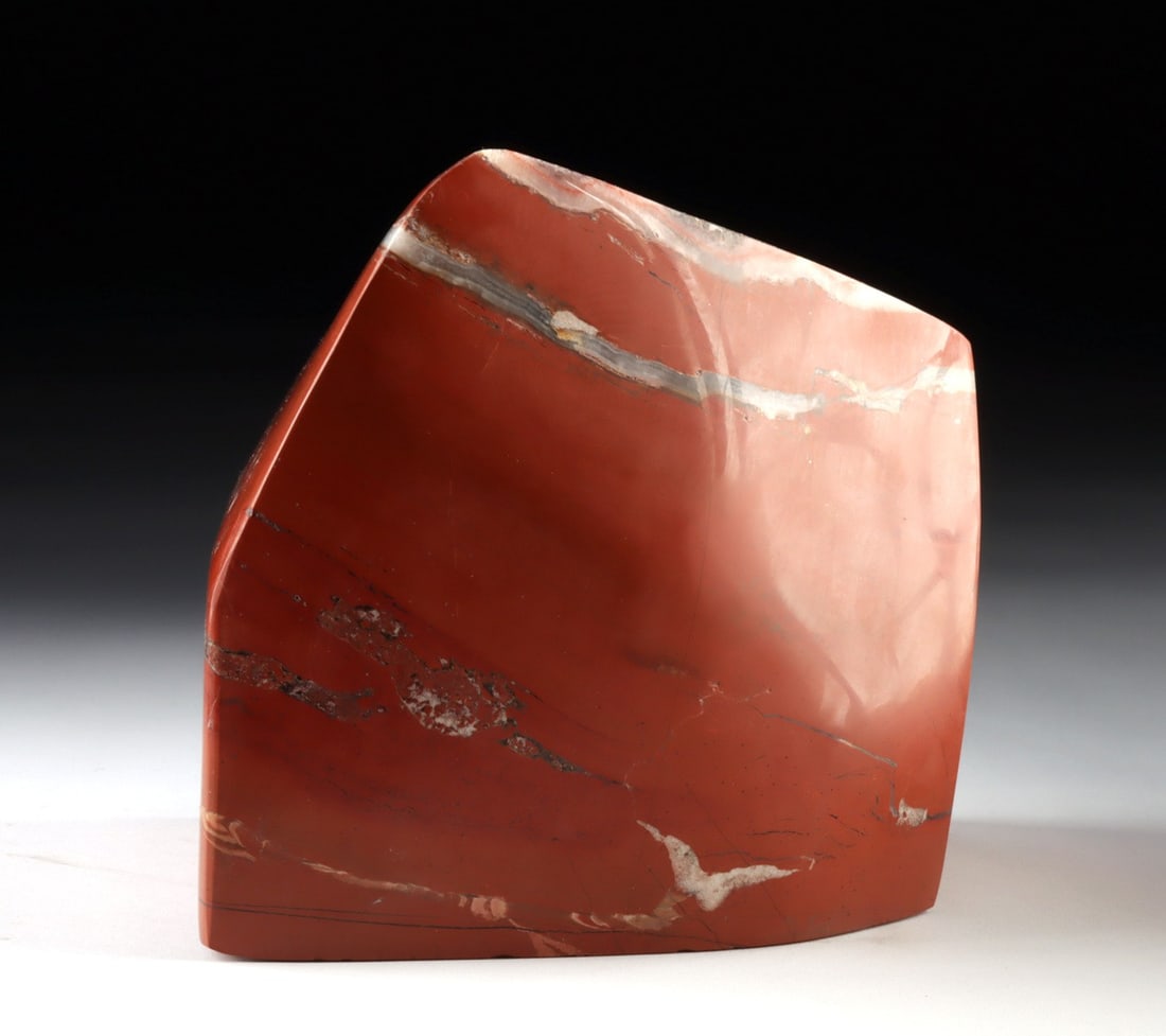 Polished Red Jasper Freeform Display Specimen: Ancient Earth, likely North Africa or South Asia, Precambrian to Paleozoic era, ca. 300 to 600 million years ago. A substantial freeform specimen of red jasper, its surfaces brought to a deep mirror p