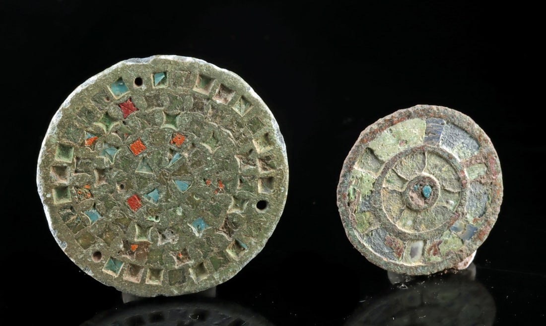 Pair of Roman Bronze and Lead Enamel Brooches: Roman, Imperial period, ca. 1st to 3rd century CE. A vibrant pair of circular Roman brooches, each cast in bronze and delicately inlaid with lead-based enamel. Both pieces display concentric geometric