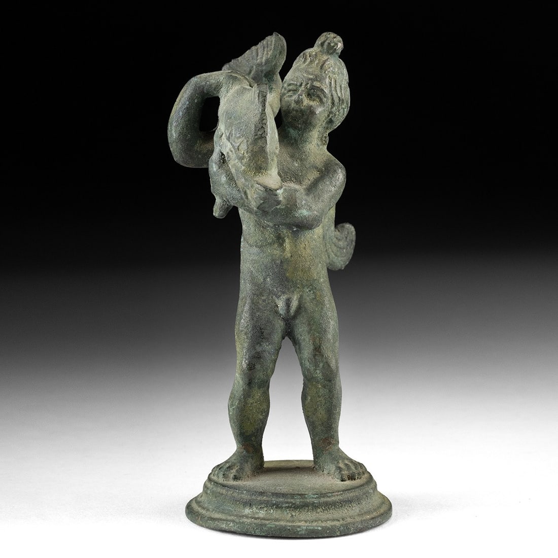 Late 19th C. Neapolitan Brass Cupid with Dolphin - Grand Tour, After the Antique: Southern Europe, Italy, Naples, Grand Tour, ca. 1880–1920 CE. A winged Cupid stands poised upon a stepped circular base, a plump dolphin gathered in his arms and lifted toward his shoulder as th