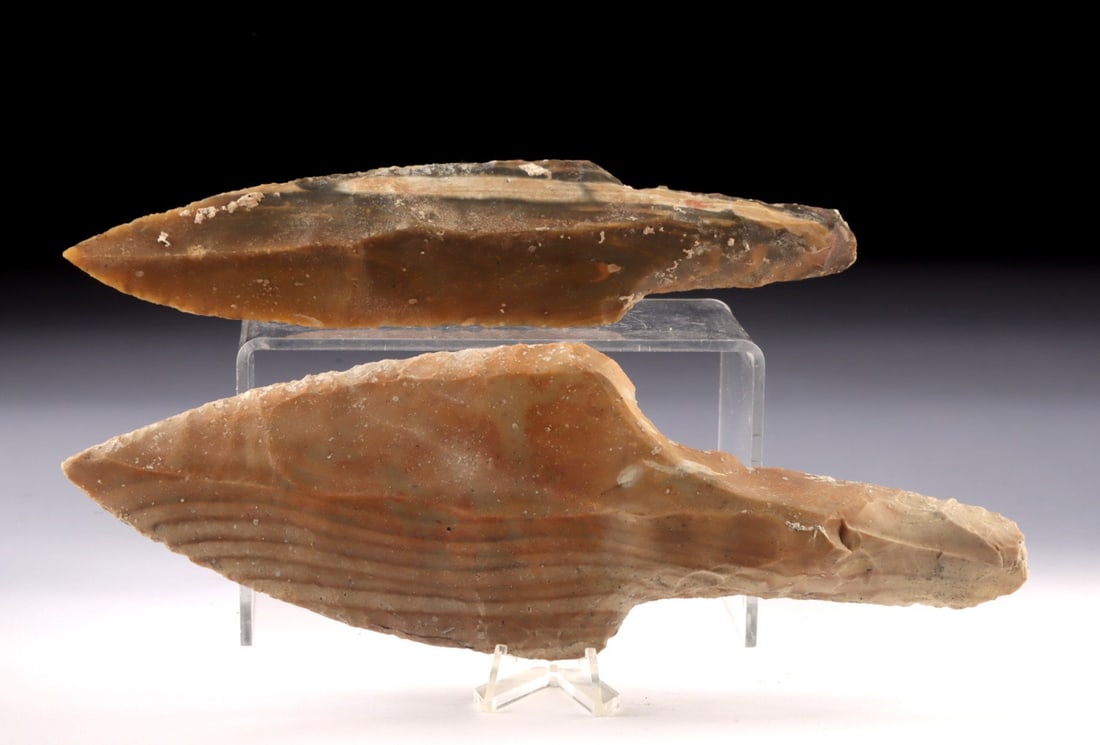 Two Large Maya Knapped Chert Ceremonial Blades: Pre-Columbian, Belize, Maya culture, ca. 600 to 900 CE. A pair of large chert ceremonial blades, each flaked in uniface form with broad triangular profiles and tapered points. Both show bold percussio