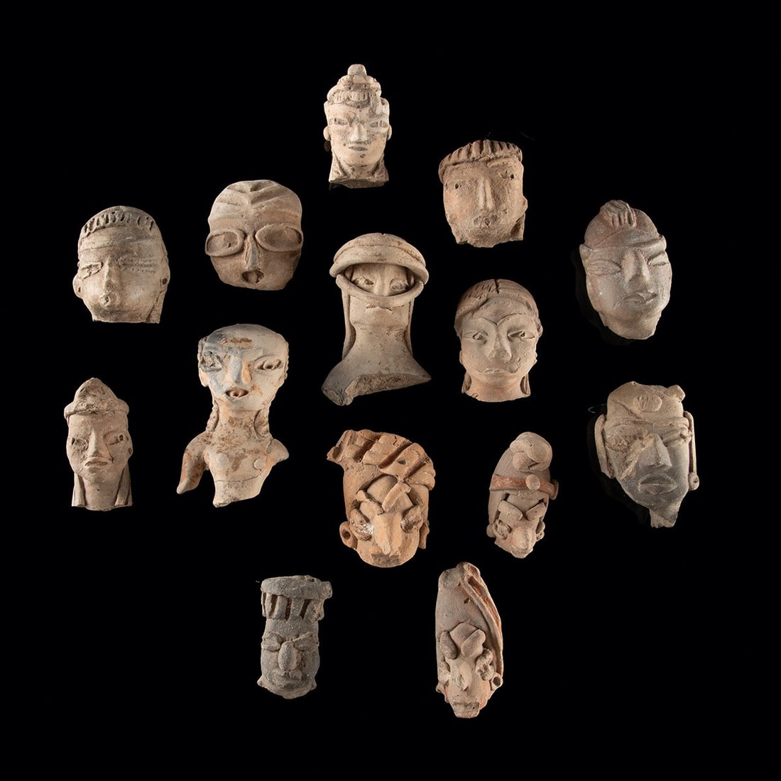 Ancient Mesoamerican Pottery Figure Head Fragments: Pre-Columbian, West Mexico, ca. 300 BCE – 300 CE. A group of fourteen pottery head fragments from ancient West Mexico shaft tomb cultures. Facial features include applique and incised eyes, stra