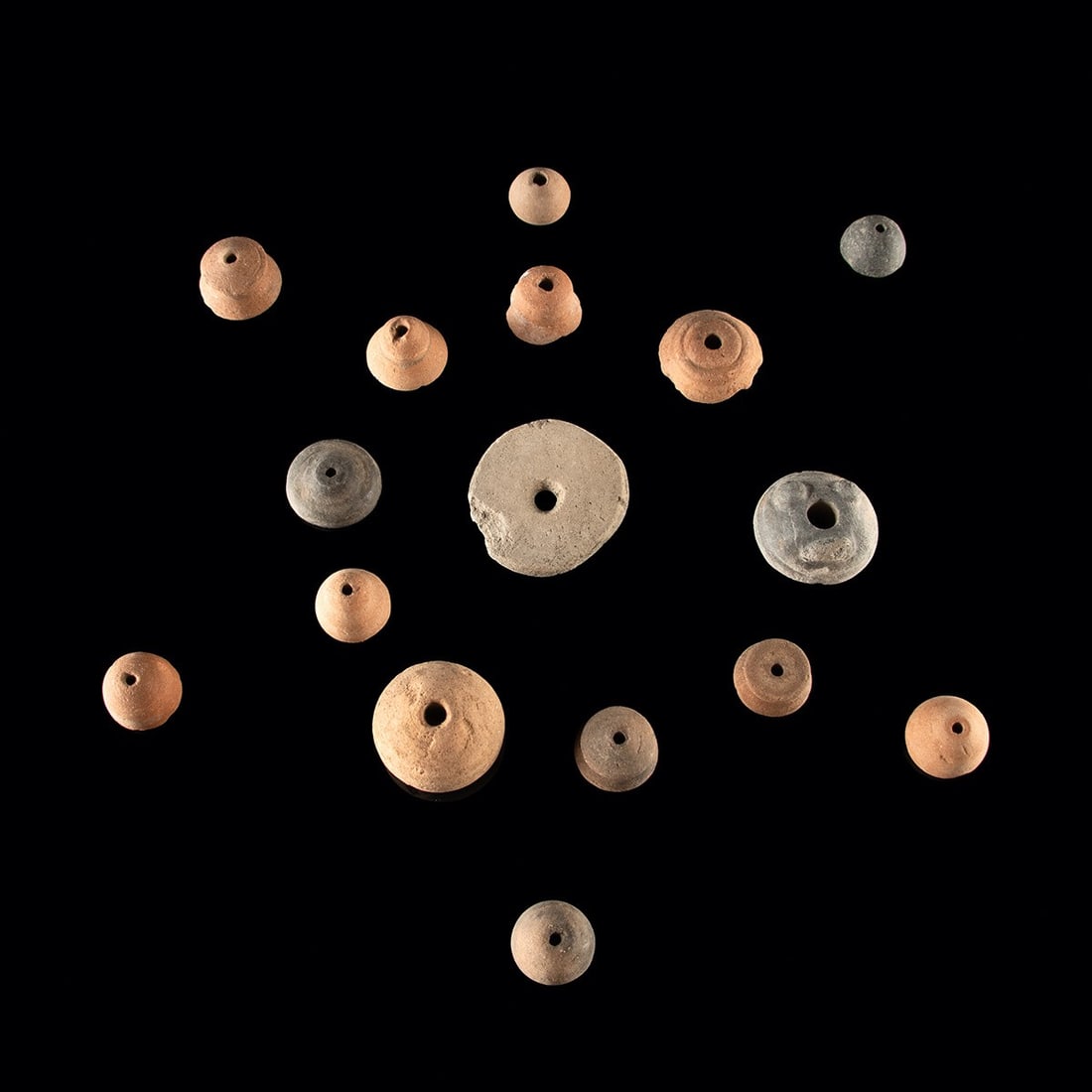 Mesoamerican Pottery Spindle Whorl Group - Sixteen Redware & Blackware Beads: Pre-Columbian, Mesoamerica, ca. 300 BCE – 1500 CE. A group of sixteen Mesoamerican pottery spindle whorls in redware and blackware, each pierced through the center for mounting on a spindle shaf