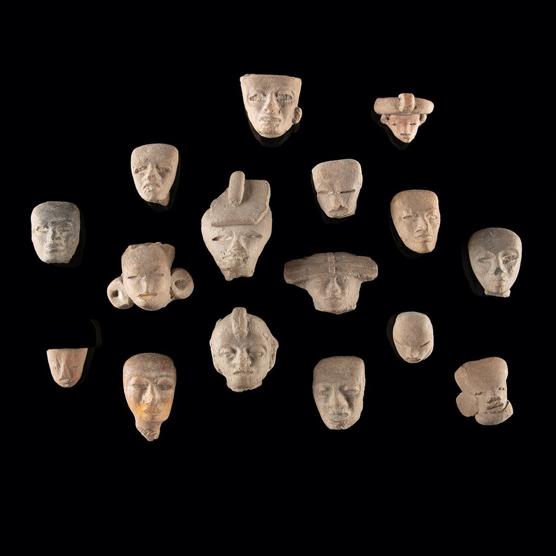 Ancient Teotihuacan Terracotta Head Fragments: Pre-Columbian, Mexico, Teotihuacan, ca. 100 BCE – 650 CE. A gathering of small terracotta heads, each from a figurine body and worn soft by the centuries. Molded and hand-modeled brows, eyes, an