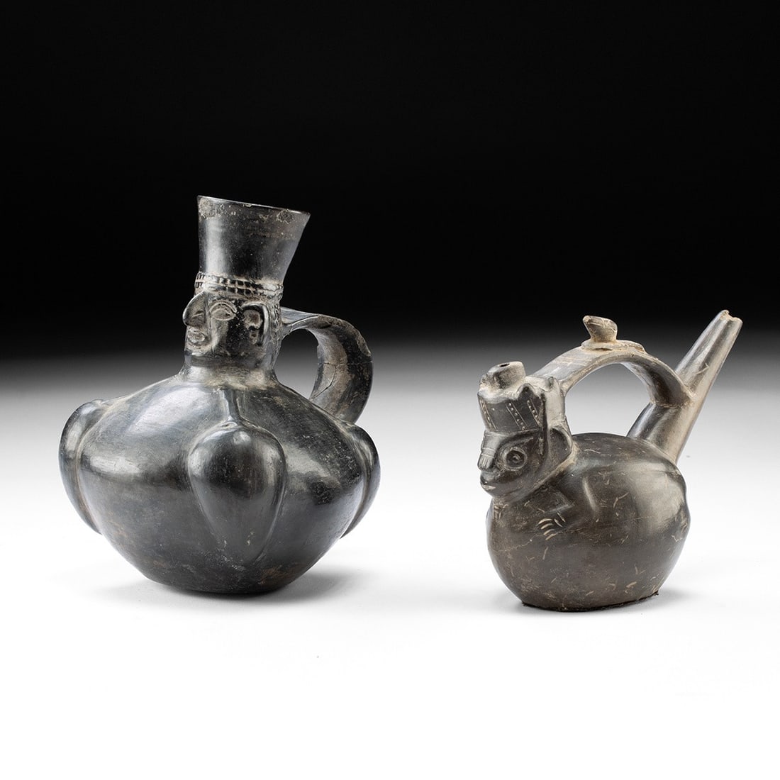 Chimu Blackware Vessels - Lord Effigy & Monkey Stirrup-Spout: Pre-Columbian, Peru, Chimu, ca. 1100–1470 CE. A pair of reduction-fired blackware vessels whose smoky, burnished surfaces carry the sooty sheen prized across Peru's north coast. The larger takes