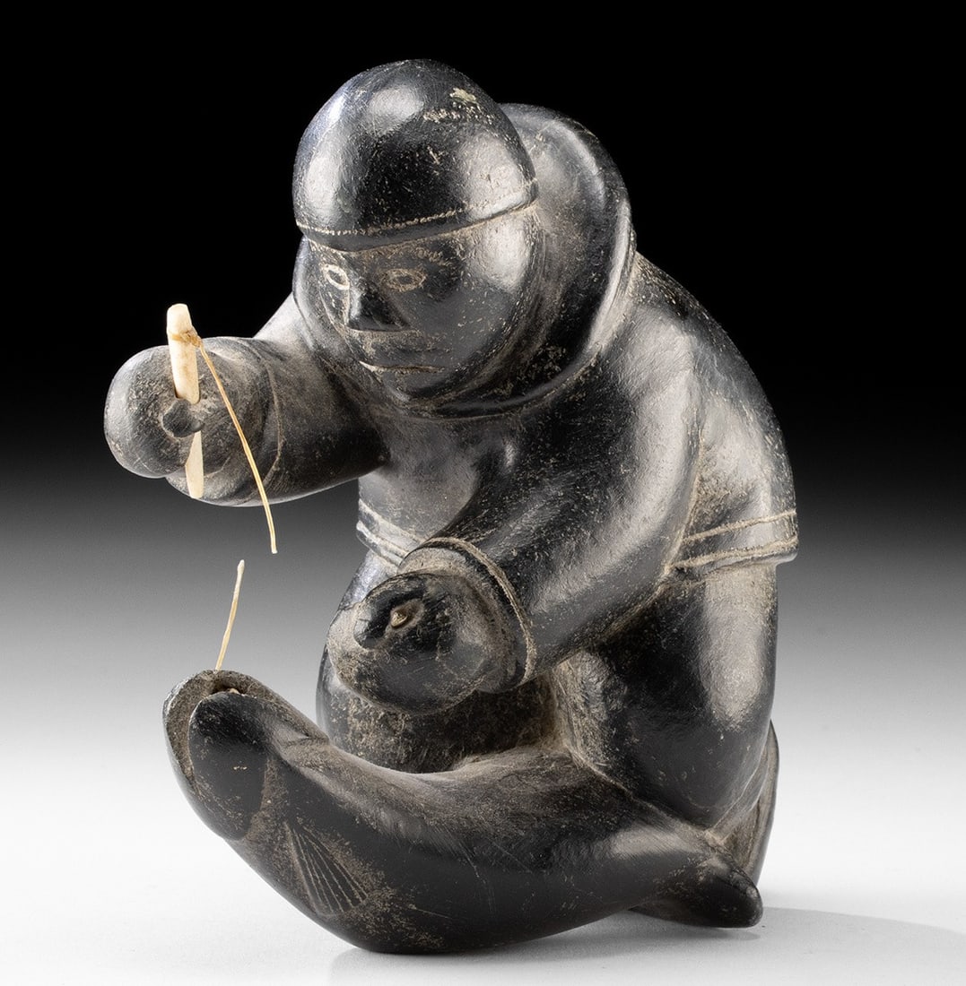 Inuit Soapstone Carving - Fisherman Catching a Salmon: Native American, Canada or Alaska, Inuit, ca. mid-20th century CE. A soapstone sculpture of a fisherman with salmon, unsigned, yet executed with great skill and movement. The figure is depicted kneeli