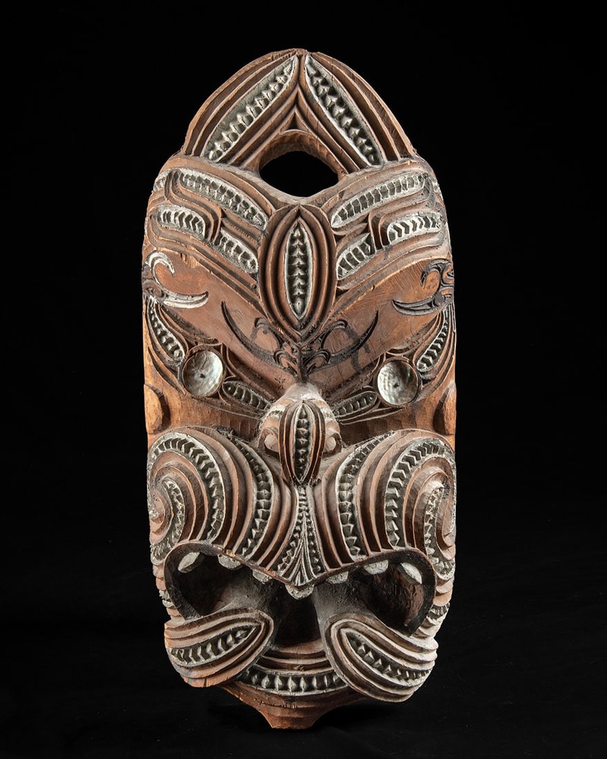 Maori Carved Wood Koruru Gable Mask - Ancestral Guardian + Paua Shell Eyes: Oceania, New Zealand, Maori, ca. mid to late 20th century CE. A large carved wooden Maori head, or koruru, worked in deep relief with sweeping double spirals across the cheeks, notched taratara-a-kae 