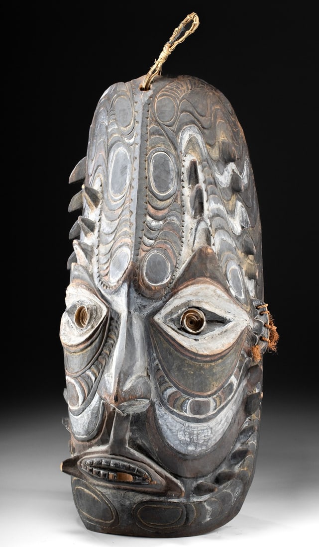Large Papua New Guinea Wood Ancestral Spirit Face: Oceania, Papua New Guinea, Sepik River region, ca. 20th century CE. A massive wooden mask depicting an ancestral face spirit, deeply carved with bold ovoids, flowing curvilinear motifs, and raised nod