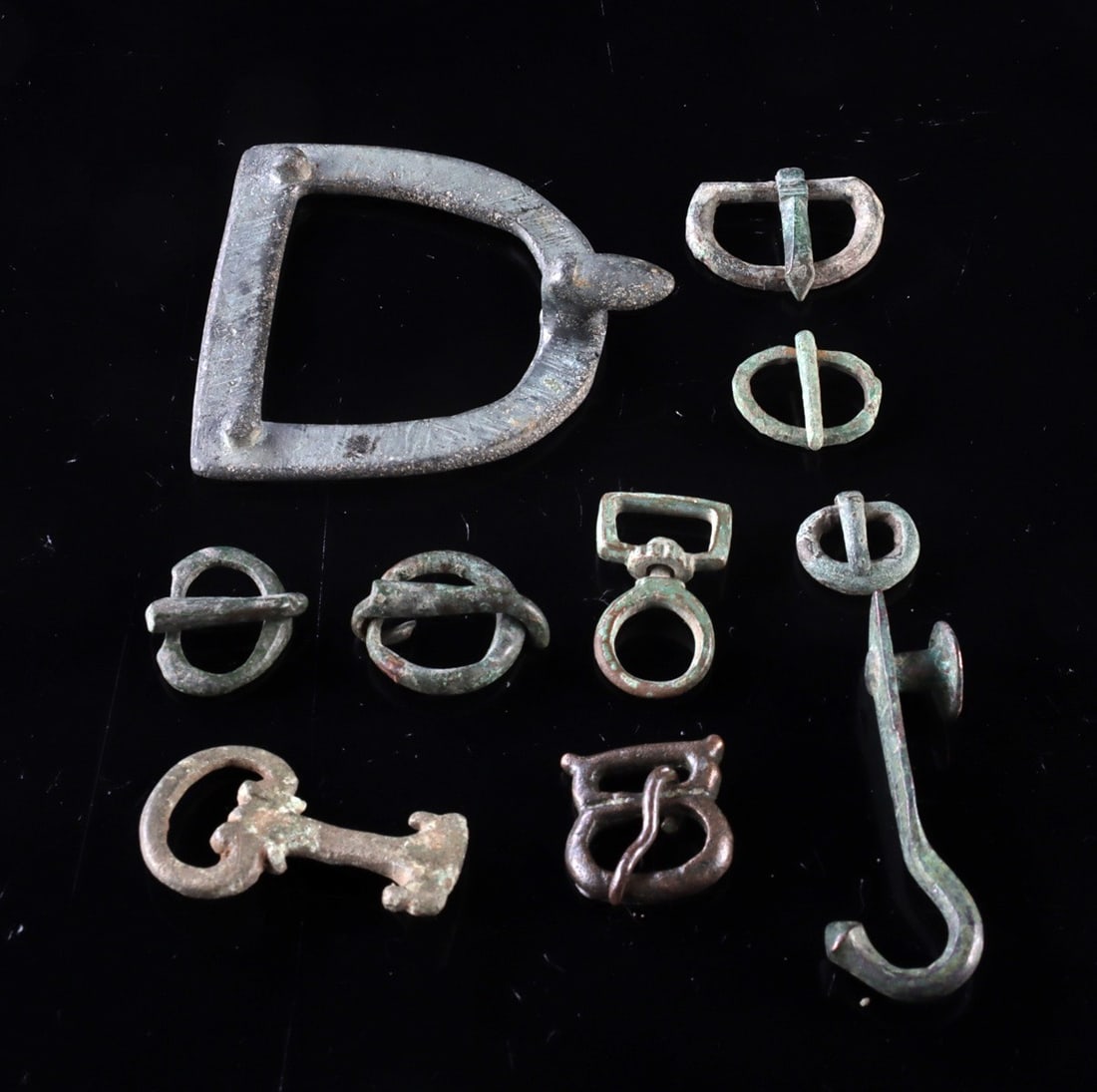 10 Roman Bronze Belt Buckles, Clasps & Attachments: Roman, Imperial period, ca. 1st to 3rd century CE. A varied group of ten Roman belt components including buckles, clasps, attachment fittings, and a decorative hook, cast in bronze and related copper 