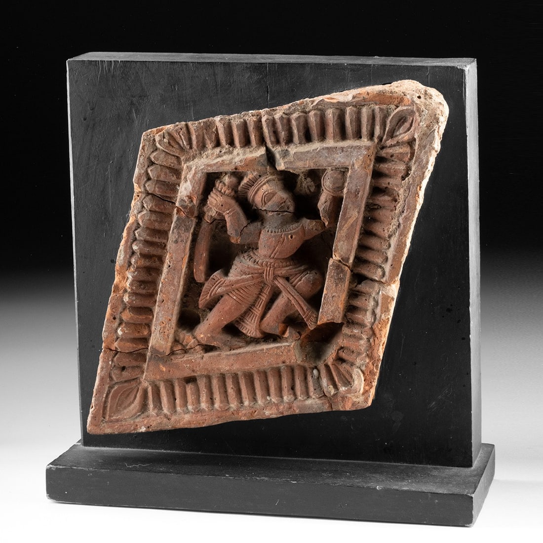 17th C. Bengal Terracotta Temple Tile - Warrior with Sword: South Asia, Eastern India, Bengal, ca. 1600–1799 CE. A molded terracotta plaque holds a warrior in mid-stride, sword lifted overhead and rounded shield raised in the opposite hand, his body coil