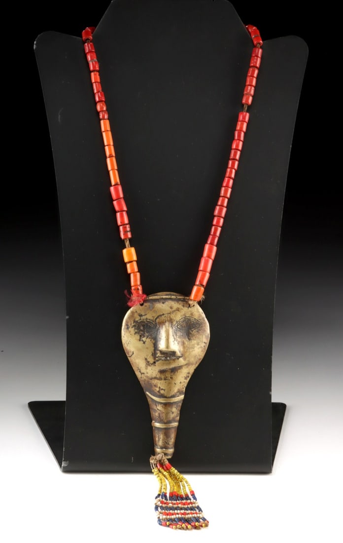Naga Headhunter Trophy Brass Pendant & Beaded Necklace: South Asia, Northeast India / Burma, Nagaland, Konyak Naga people, ca. 19th to early 20th century CE. A brass pendant cast in the form of a stylized conch shell, its surface worked with a human visage