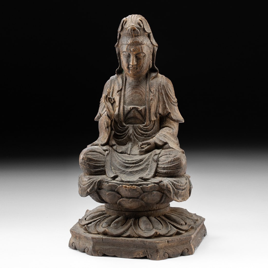 Chinese Carved Wood Guanyin - Seated Bodhisattva on Lotus Throne: East Asia, China, Qing Dynasty, ca. 19th century CE. A Chinese carved wood figure of Guanyin, the bodhisattva of compassion, seated in dhyanasana on a lotus throne raised on a hexagonal petal-carved b