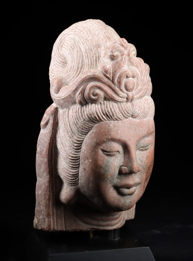 Lifesize++ Chinese Stone Head of Guanyin: East Asia, Chin, ca. 1st half of 20th century CE. A large carved stone head depicting Guanyin (Avalokiteshvara), shown with a serene downcast gaze and softly modeled facial features. The hair is gathe